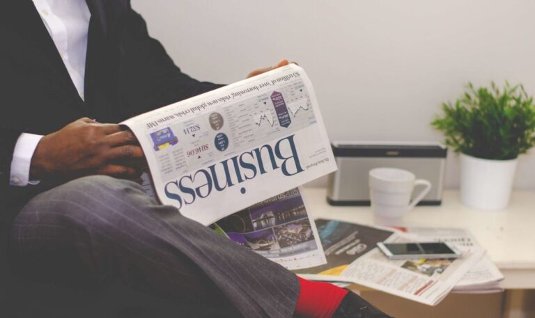 Investor reading a business newspaper at a desk before the trading week