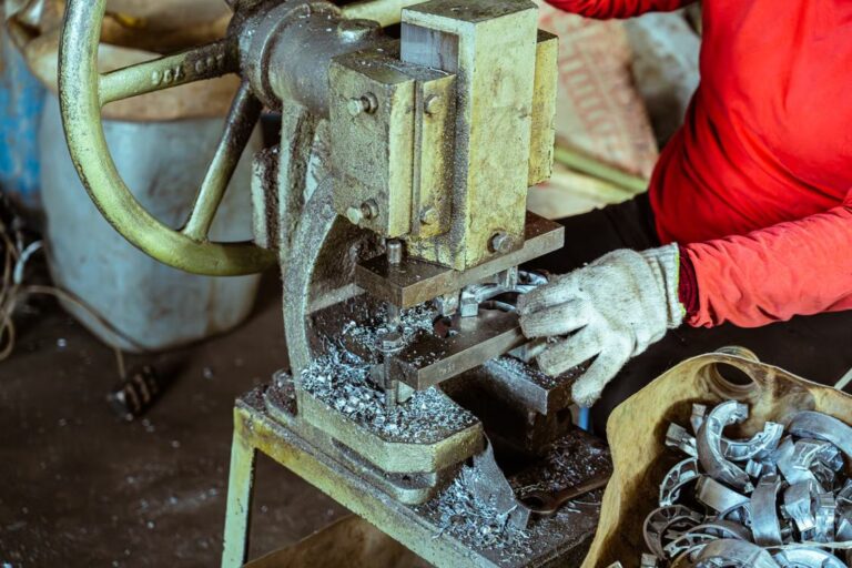 Worker operating a metal press machine in a factory
