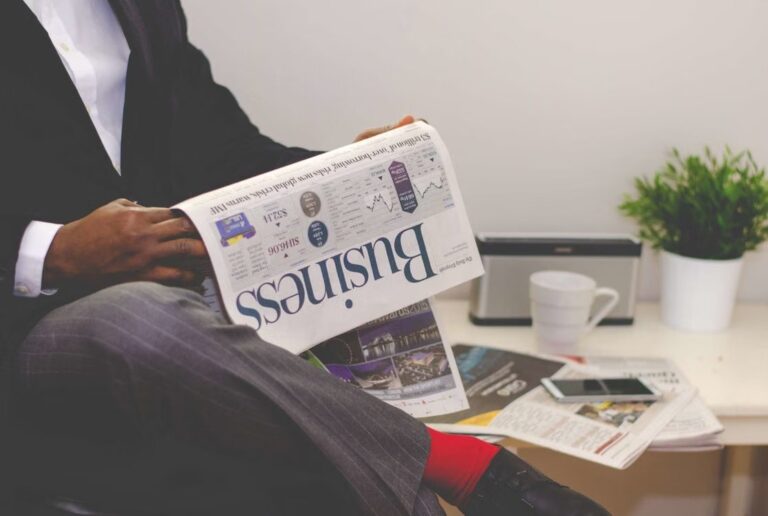 Business reader reviewing a financial newspaper at a desk