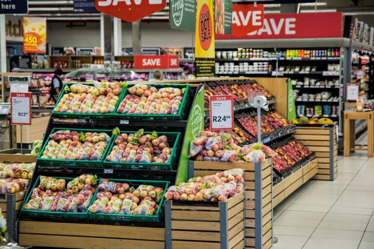 Supermarket produce displays with packaged apples and price signs
