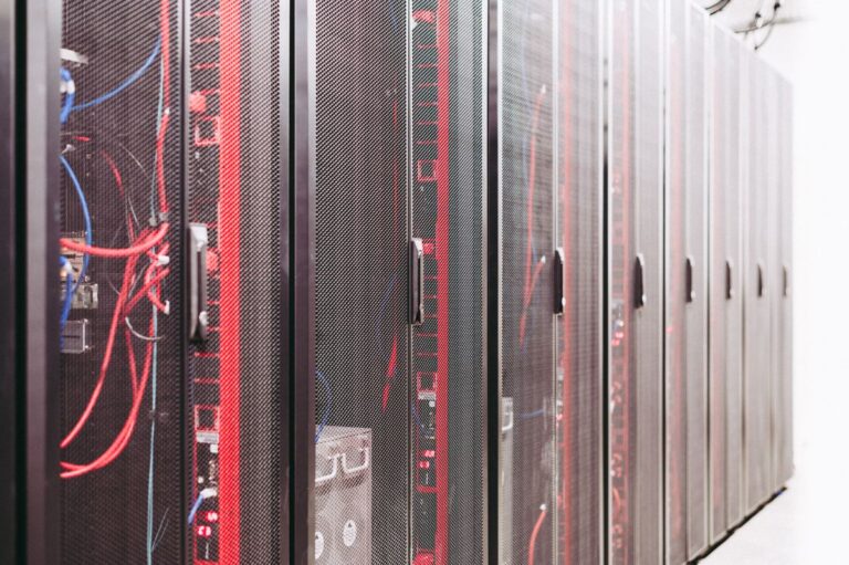 Rows of black server cabinets with red and blue cables in a data center