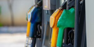 Close-up of yellow, green and blue fuel nozzles hanging on a gas station pump