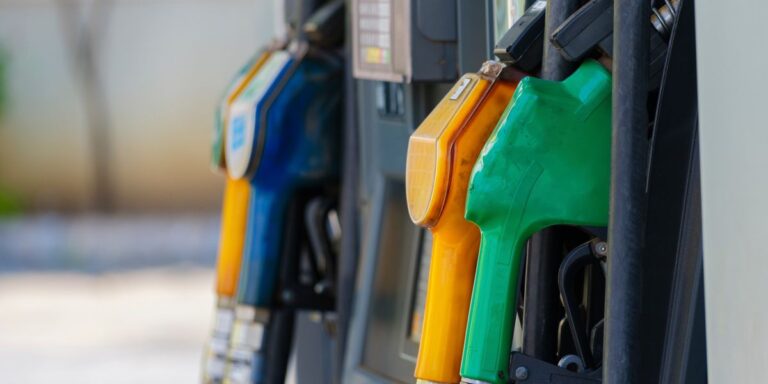 Close-up of yellow, green and blue fuel nozzles hanging on a gas station pump